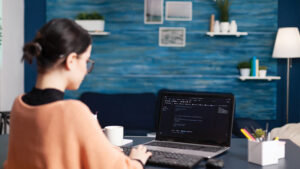 Realistic image of a person’s hand resting on a laptop keyboard with one finger of another hand approaching a search bar with the words “AI Search.