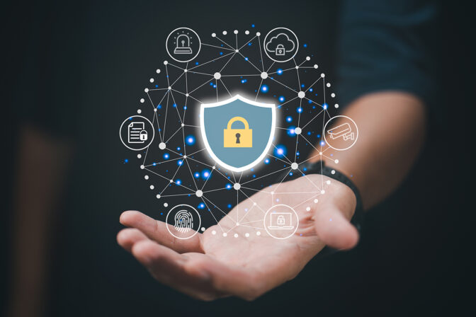 The image depicts a hand with a graphic overlay representing cybersecurity concepts. A shield icon with a lock symbol is central, surrounded by interconnected nodes symbolizing a network, each with icons such as a key, a padlock, a document, and a shopping cart, indicating various aspects of digital security. The background is dark, focusing the attention on the hand and the network of security symbols.