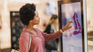 A shopper engages with an interactive digital signage kiosk, showcasing best practices in digital signage with its user-friendly interface and clear, vibrant graphics that enhance the customer experience in a modern retail setting.