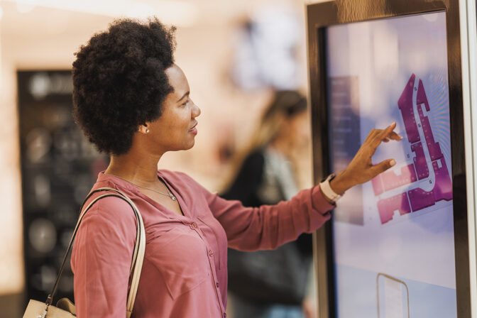 A shopper engages with an interactive digital signage kiosk, showcasing best practices in digital signage with its user-friendly interface and clear, vibrant graphics that enhance the customer experience in a modern retail setting.