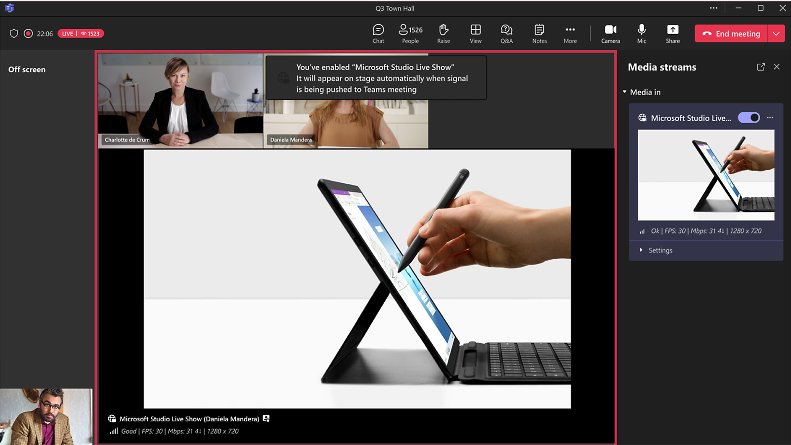 A Microsoft Teams town hall meeting interface showing a live stream with multiple presenters. One presenter is on the main stage, and another is on a smaller side view. A media stream panel is visible on the right, displaying a stylus being used on a tablet screen.