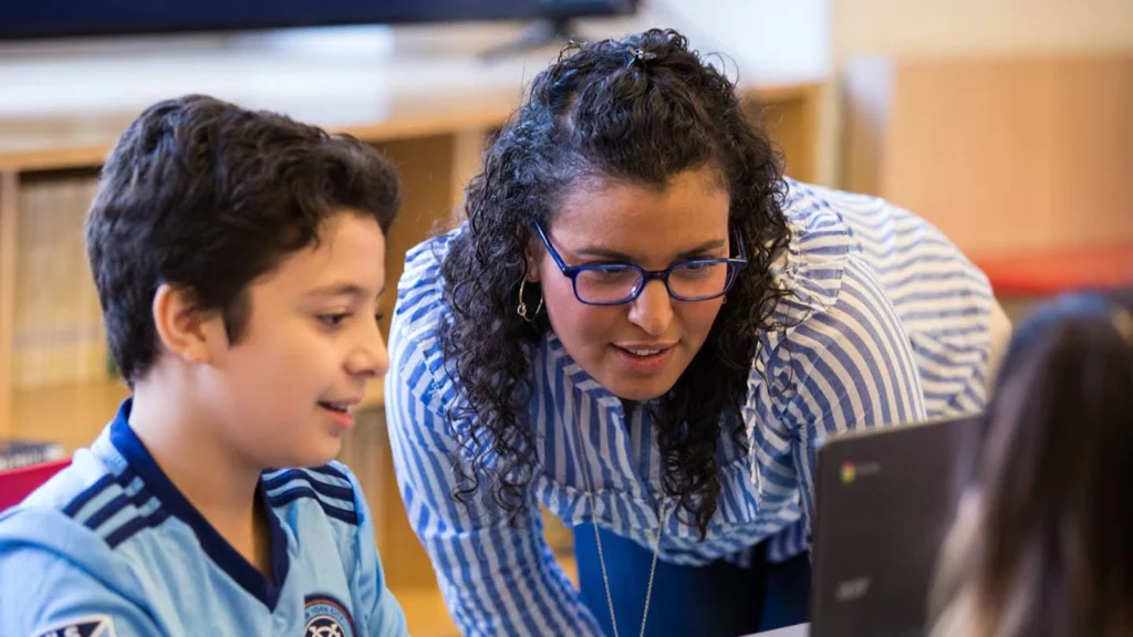 Teacher actively teaching a student using a Google Chromebook.