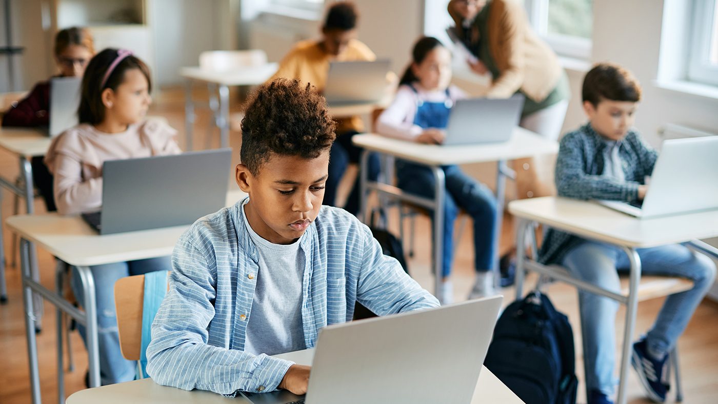 African American schoolboy e-learning on laptop during computer class in the classroom.