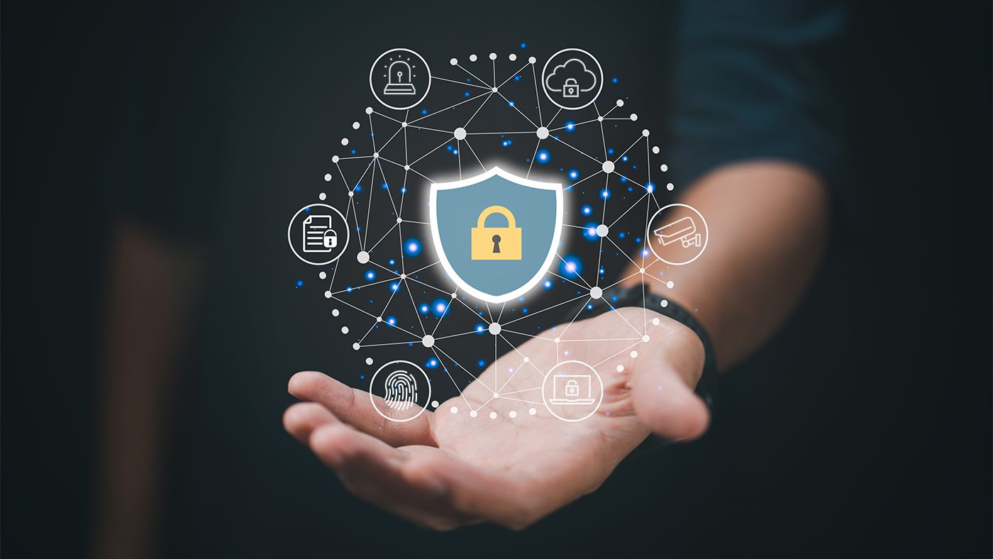 The image depicts a hand with a graphic overlay representing cybersecurity concepts. A shield icon with a lock symbol is central, surrounded by interconnected nodes symbolizing a network, each with icons such as a key, a padlock, a document, and a shopping cart, indicating various aspects of digital security. The background is dark, focusing the attention on the hand and the network of security symbols.